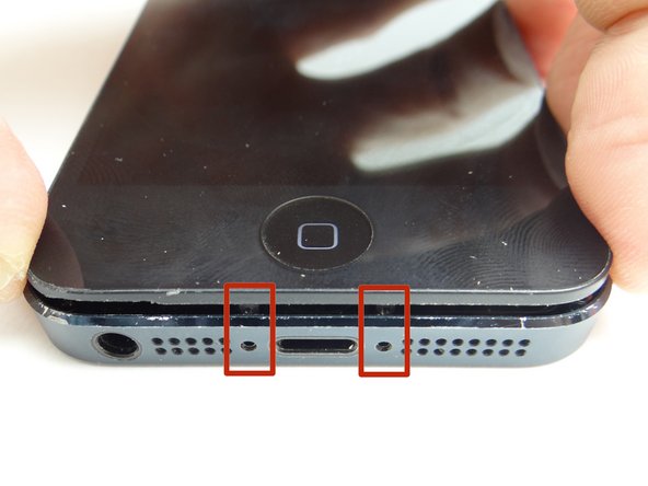 Picture 1: With the phone on the worktable, push the Pentalobe screw tabs in first.