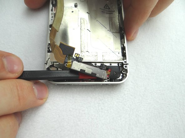 Use the flat edge of the Black Spudger to loosen the adhesive holding the charging port to the mid-frame.