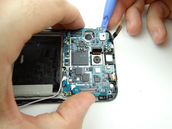 Picture 1: Pinch the logic board with one hand while lifting the top-left edge with a blue pry tool.