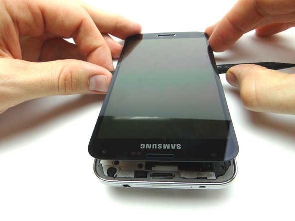 Picture 1: Use the spudger to work your way through the adhesive, top to bottom, stopping two-thirds of the way down.