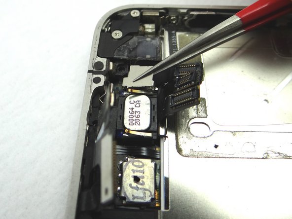 Using Curved Tip Tweezers, replace the front-facing camera plate from COMPARTMENT E.