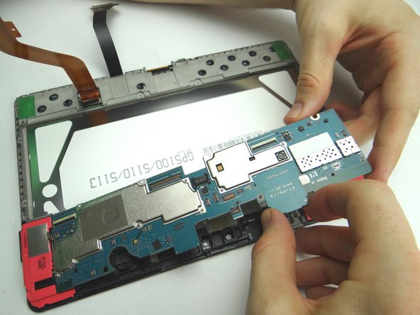 Picture 1: Wedge the flat end of the spudger under the top edge of the logic board as shown.  Pry up just enough to pinch the logic board with your fingers.
