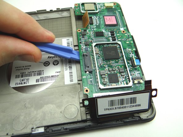 Picture 3: The bottom of the logic board is lightly adhered to the mid-plate.  Wedge the wide blue pry tool exactly where shown.  Gently twist counter-clockwise to lift the bottom of the board.