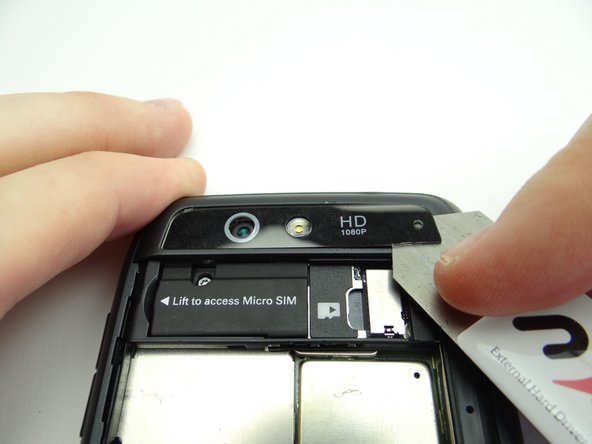 Pictures 2 &amp; 3: Wedge the iSesamo between the camera trim and rear frame in the lower-left corner.  Carefully work your way under the right side of the trim.