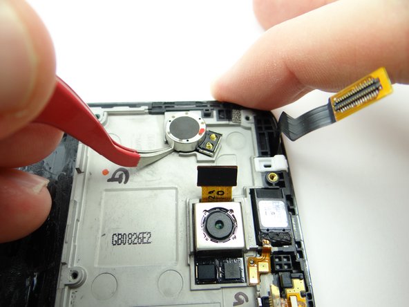 With the tweezers in the closed position, wedge under the vibrator and lift up.