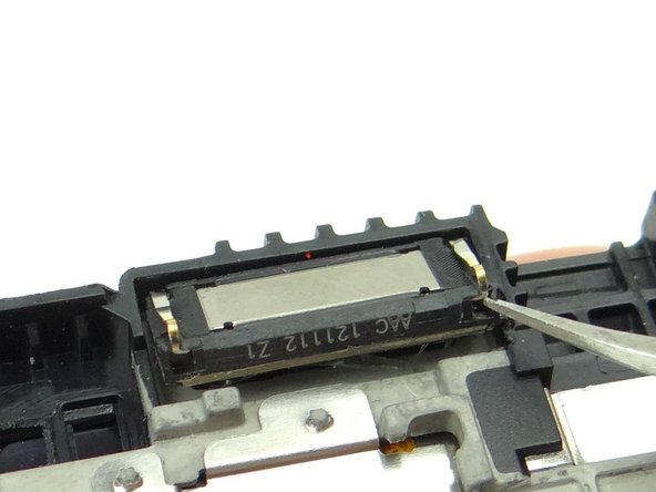 Insert one prong of the curved tip tweezers in right notch. Gently lift away the earpiece speaker.