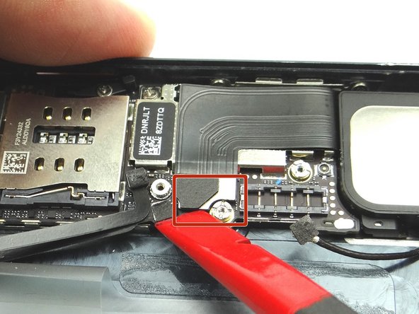 Picture 1: Place flat end of spudger under left side of charging port assembly cable. Gently twist your hand clockwise releasing the cable from its socket on the logic board.