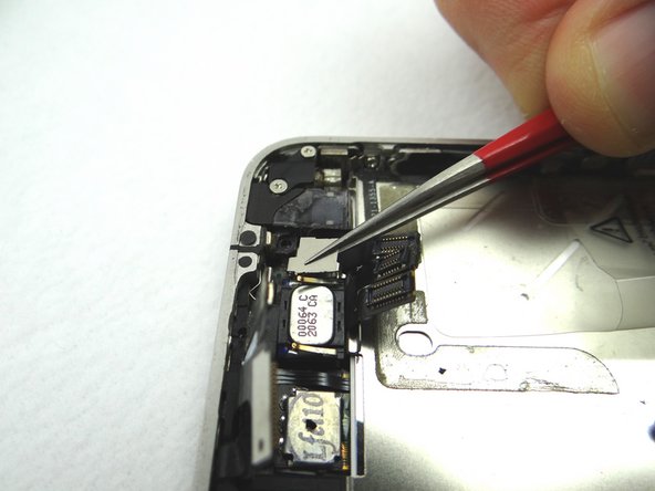 Pictures 1 and 2: Use a pair of tweezers to remove the metal plate covering the front facing camera; pull the bottom clip free first, then push the plate towards the top of the iPhone to free the top left clip, then pivot right to free the top right clip.
