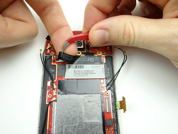 Picture 1: Take care not to touch the logic board as you pinch the upper-left corner of the IMEI sticker with curved tip tweezers.  Peel it up until you can wedge your finger under the sticker.