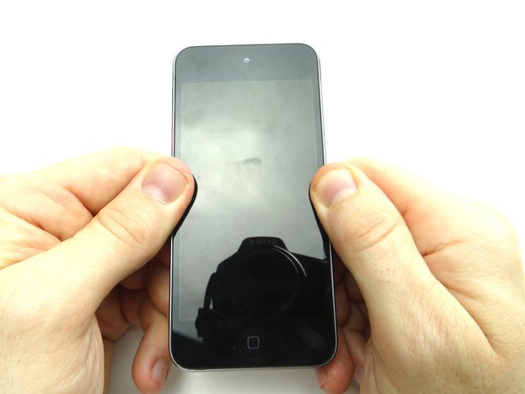 Press firmly on either side of the home button where the adhesive pads are located.