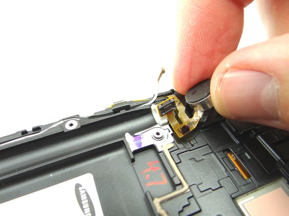 Once the vibrator is up, grab it with your index finger and thumb, and gently pull the remaining ribbon cable from the phone. Place in COMPARTMENT D.