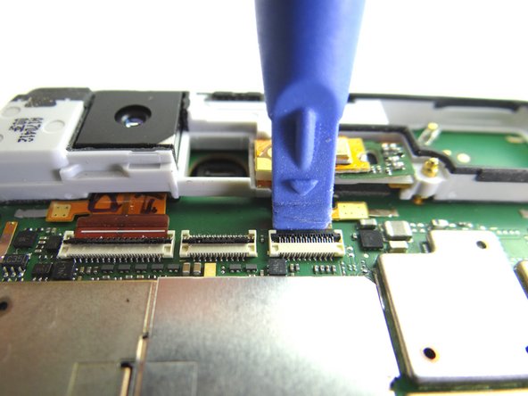 Picture 1: Place blue pry tool under black swing bar of ZIF connector and lift up to open it.  Push the cable out of the connector.