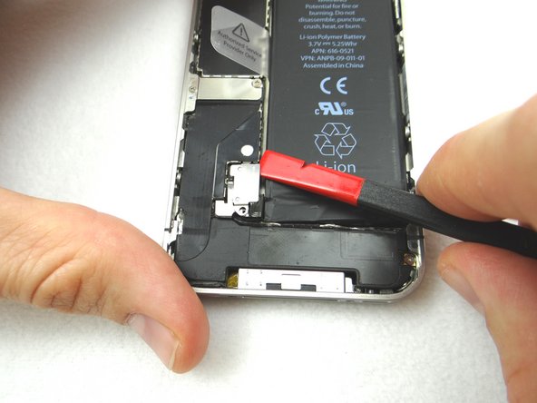 Picture 2: Place the flat end of the Black Spudger (tip is painted red for better illustration) at the top of the battery connector. Gently twist the spudger counter-clockwise to lift the connector from its socket.