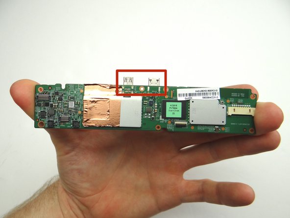 Picture 2: Grab the logic board with your fingers and carefully guide the charging port and HDMI port (red square) out of their sockets.  Finish removing the logic board.