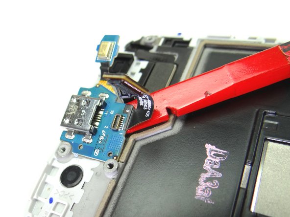 Wedge spudger under charging port and sweep under to free it from the adhesive holding it in place.