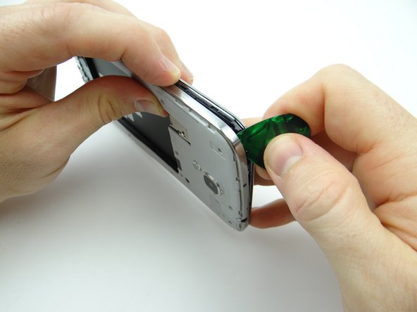 Picture 2: Gently tug on the mid-frame with one hand to create space, then reinsert the guitar pick in the corner above the power button with the opposite hand.