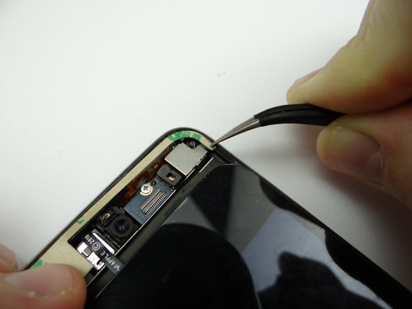 Picture 1: Place thin adhesive strip at the top of the rear case.  Use your fingers to place the upper-left corner and curved-tip tweezers to place the upper-right corner.  Peel off the paper backing.