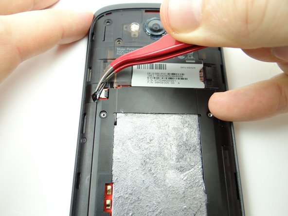 Use curved tip tweezers to peel up electrical tape covering volume cable connector.  Adhere tape to wall of COMPARTMENT B.