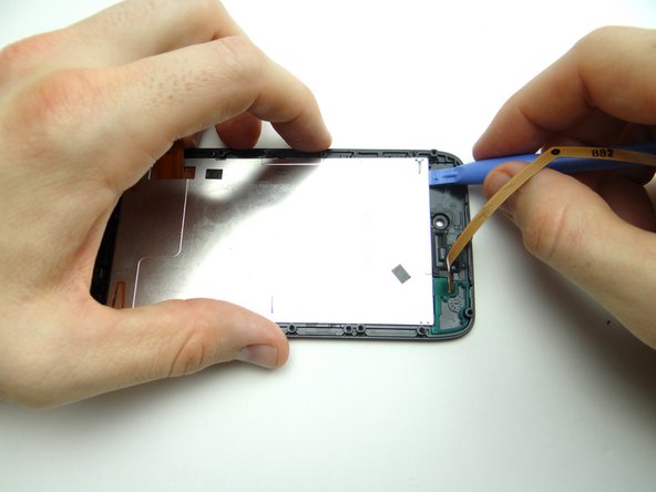 Use a blue pry tool to carefully lift the top edge of the LCD until you can grab the sides with your fingers.