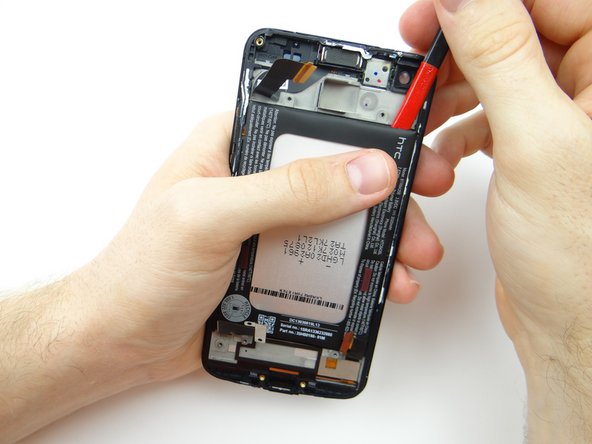 Picture 2: Use the flat end of the spudger to push halfway down the adhesive.