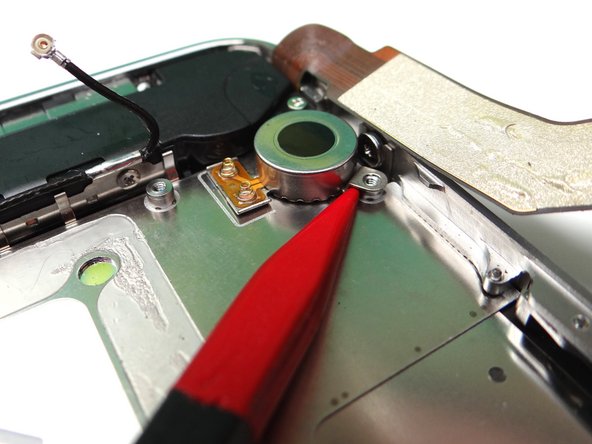 Picture 1: Wedge the pointed tip of the Black Spudger under the lip of the vibrator.  Gently lift to loosen the adhesive holding the vibrator to the mid-frame.