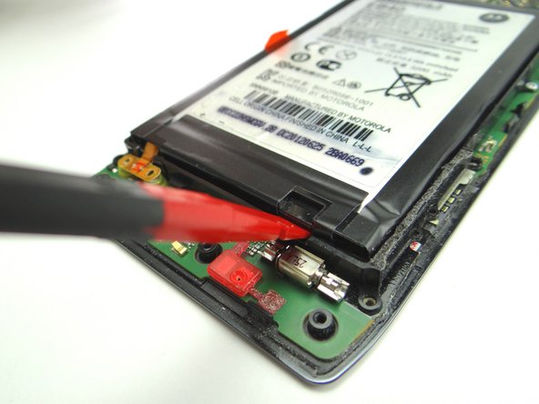 Pry up around the edges to free the adhesive holding down the battery.