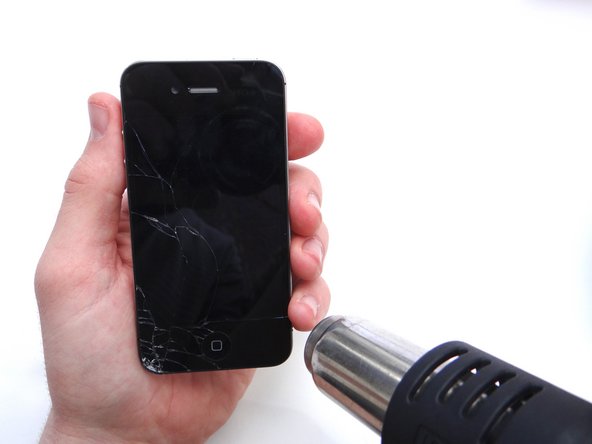 Picture 1: Apply low heat (100 degrees celsius) to the top and bottom edges of the iPhone, sweeping back and forth to loosen adhesive.  Continue for two minutes.