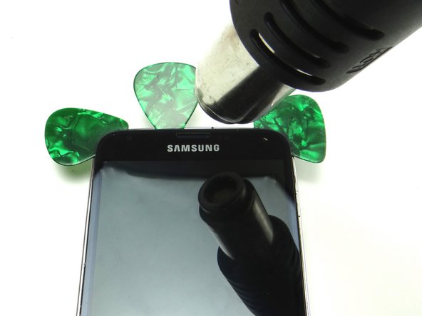 Heat the top edge and insert a guitar pick just left of the earpiece speaker.