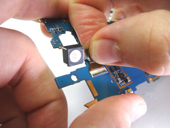 Open rear camera ZIF connector with blue pry tool.