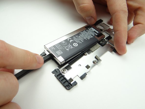 Turn the spudger to cut through the adhesive holding the battery.