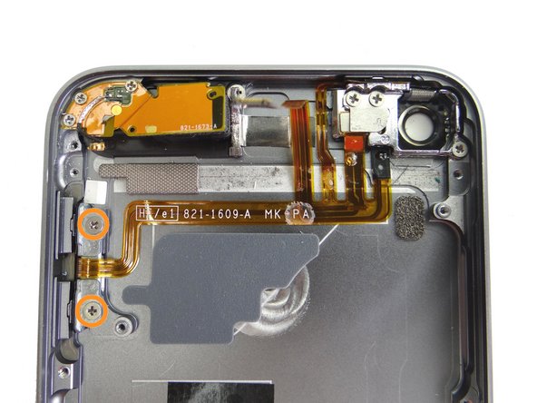 Replace two 2.0 mm #00 Phillips screws securing the volume button end of the button ribbon cable to the rear case from SLOT 7.