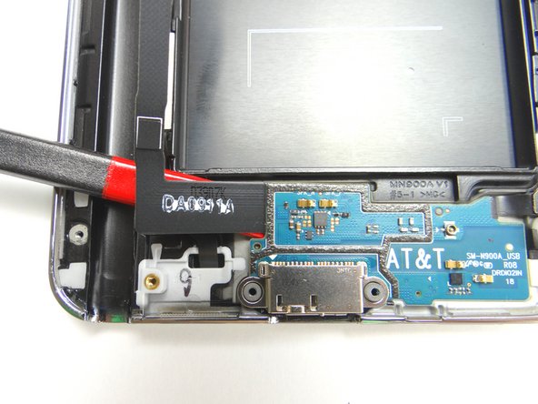 Use the flat end of the spudger to wedge underneath the top-left edge of the charging port.