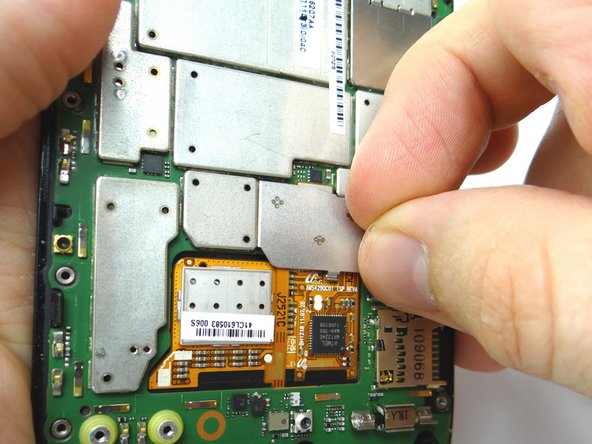 Remove the metal shield covering the display ribbon connectors: Use your fingernail to push down to free tab '1' first.  Then pull left to free tabs '2' and '3'. Place in COMPARTMENT F.