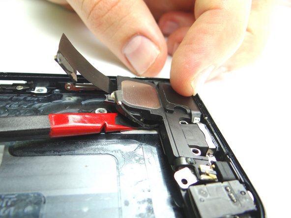 Picture 1 &amp; 2: Wedge the flat end of the Black Spudger underneath the speaker assembly / charging port and gently pry to release the adhesive, working your way from the right side of the phone to the left.