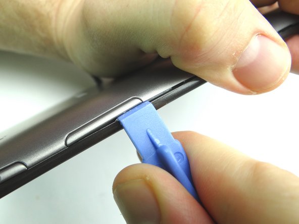 Picture 1: Insert wide blue pry tool below the bottom half of the volume rocker.