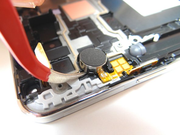 Now wedge the tweezers under the vibrator and pry up to loosen it, but don't remove it just yet.