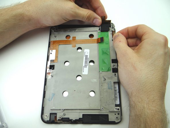 Lift the upper-right corner of the mid-plate, carefully guiding the LCD and digitizer cables through.