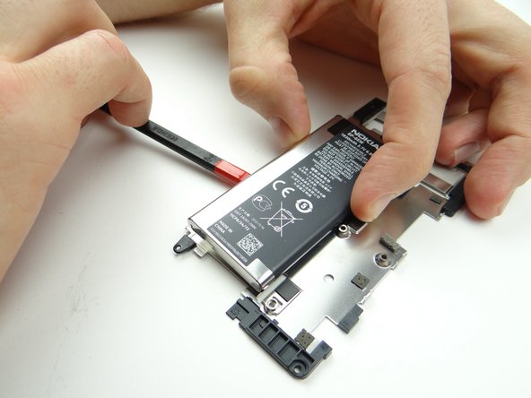 Turn the spudger to cut through the adhesive holding the battery.