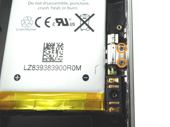Remove two 1.9 mm Phillips screws holding down vibrator (located just above the battery connector).  Place screws in COMPARTMENT B.