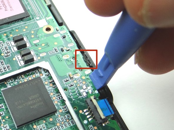 Picture 3: The bottom of the logic board is lightly adhered to the mid-plate.  Wedge the wide blue pry tool exactly where shown.  Gently twist counter-clockwise to lift the bottom of the board.