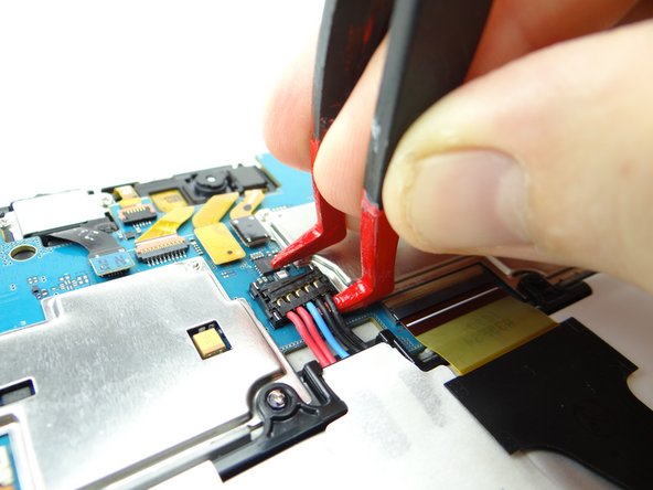 Use one prong of the plastic tweezers to wedge under the right side of the battery connector and pull it up slightly.