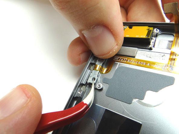 Use tweezers to lift volume button bracket out of the way just enough to allow the volume buttons to be extracted.