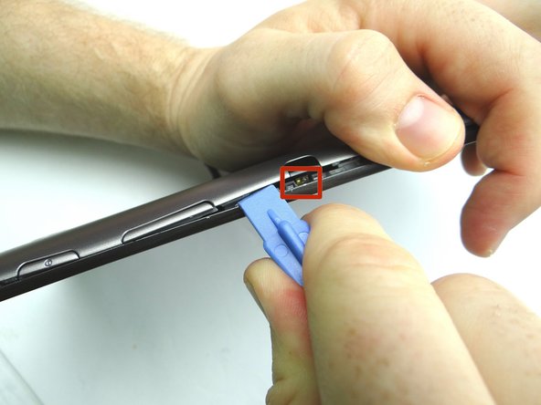 Picture 2: Sweep between the volume rocker and infrared sensor cover.  Twist counter-clockwise to pop up.  Grab the battery cover with your thumb to hold it open.