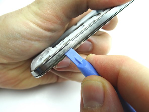 Picture 1: On the volume rocker side, near the bottom, push the blue pry tool between the front panel and mid-frame.