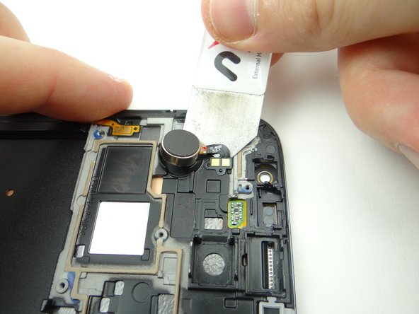 Use the iSesamo to wedge carefully under the vibrator cable.  Lift the vibrator away from the front panel.