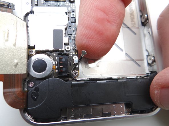 Picture 1: Using your fingers, re-route the cellular antenna cable into the metal clips attached to the logic board, first pulling cable left, then right.