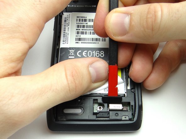 Pictures 2 &amp; 3: Use the flat end of the spudger to pry up the cover just below the '- +' signs on the battery.  Finish removing cover with your fingers and place in SLOT 1.