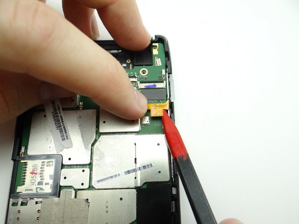 Picture 2: Use your left hand to push the cable out of the connector while gently tugging the cable with the pointed end of the spudger in your right hand.