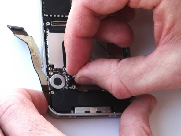 Picture 2: Use your fingers to de-route the cellular antenna cable out from under the metal clips attached to the logic board.  First pull cable right, then left.
