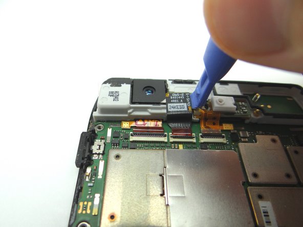 Picture 2: With the ZIF connector in the open/up position, lift the front-facing camera out of its socket with the blue pry tool.